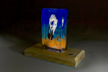 Bird skull in resin against a turbulent blue background with a timber base