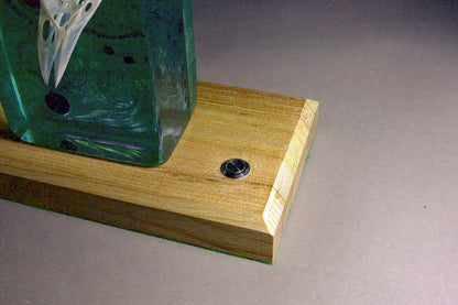 Bird skull in resin. Illuminated against a rich violet background. On a timber base